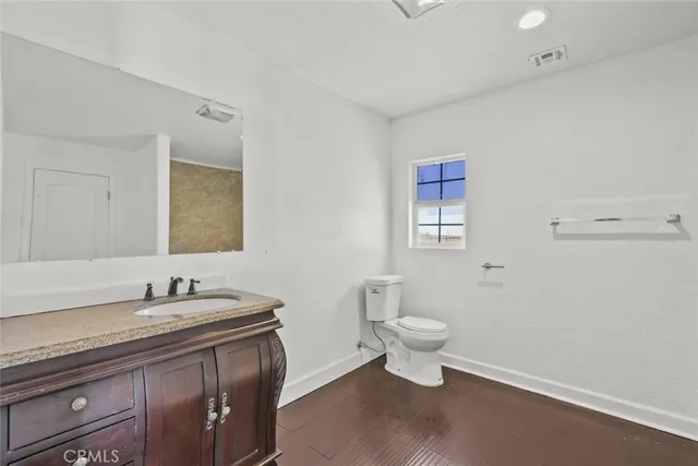 a bathroom with a granite countertop toilet a sink and a mirror