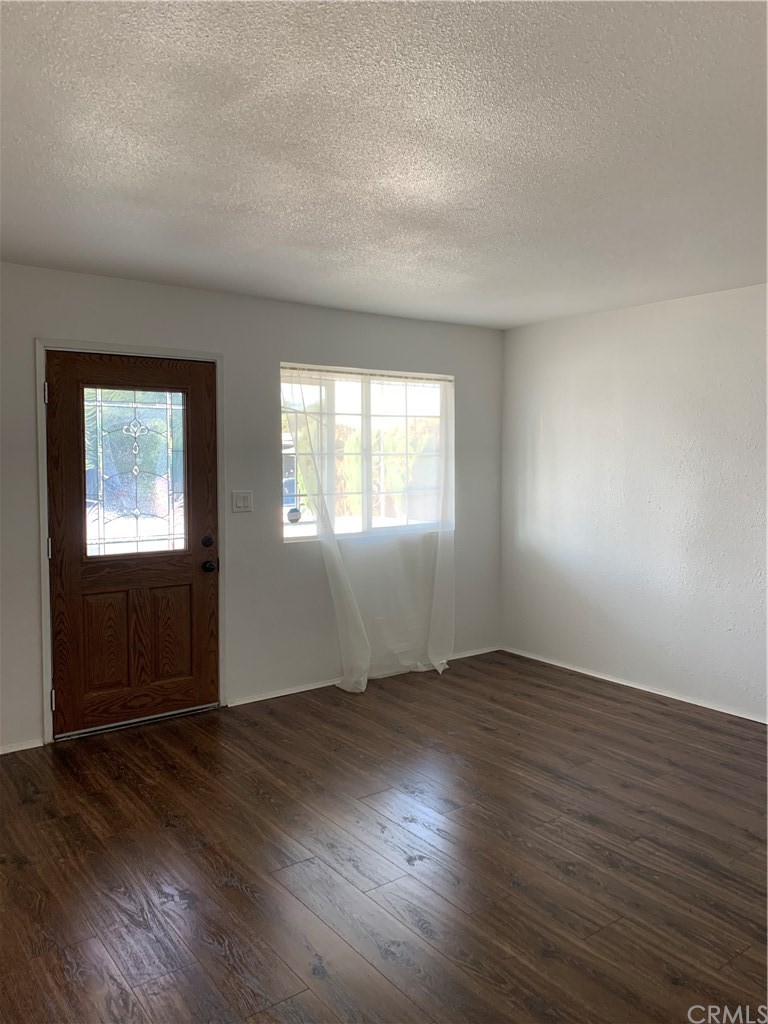 8216 Wilbarn Street Paramount, CA 90723 - Photo 8 of 27 an empty room with wooden floor and windows