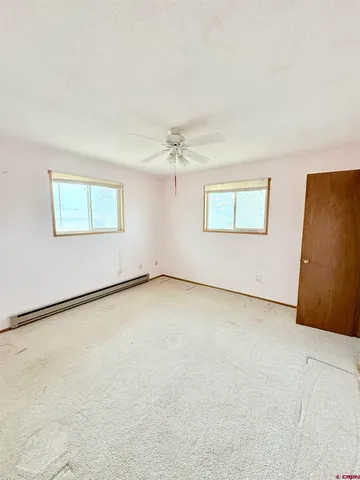 an empty room with a ceiling fan and windows