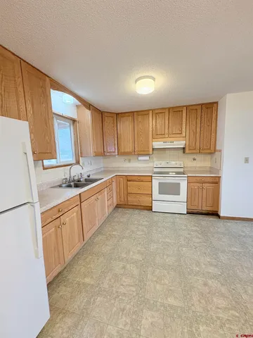 a kitchen with granite countertop a refrigerator sink and cabinets