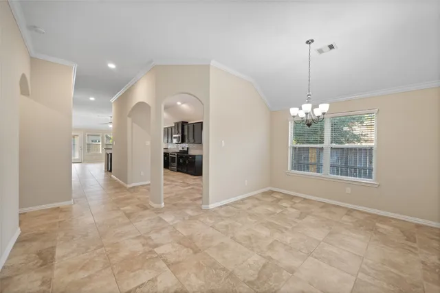 an empty room with chandelier fan and windows