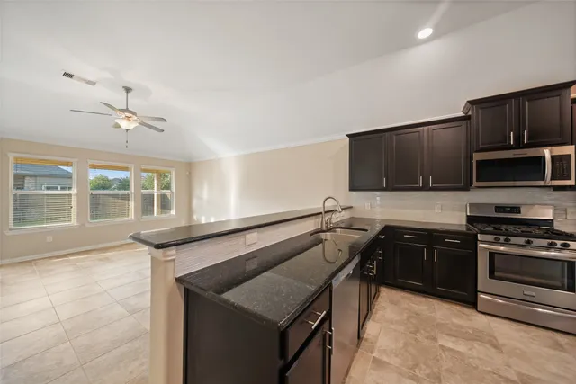 a kitchen with stainless steel appliances granite countertop a stove a sink and a microwave