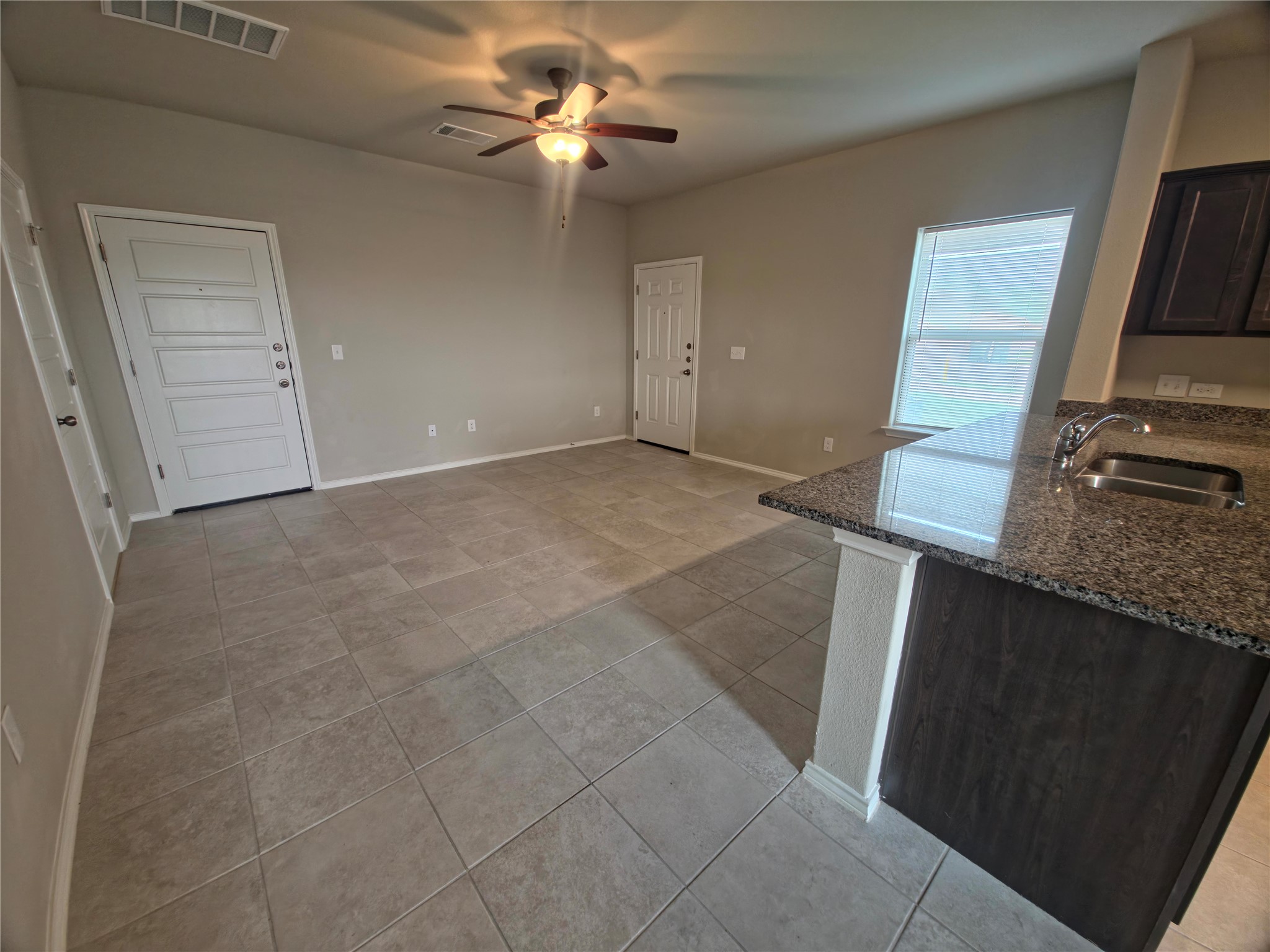 140 Dodge Road Georgetown, TX 78626 - Photo 3 of 14 Open concept living space featuring tile flooring, vaulted ceilings, a ceiling fan, and an integrated kitchen island with a double basin sink and granite countertop