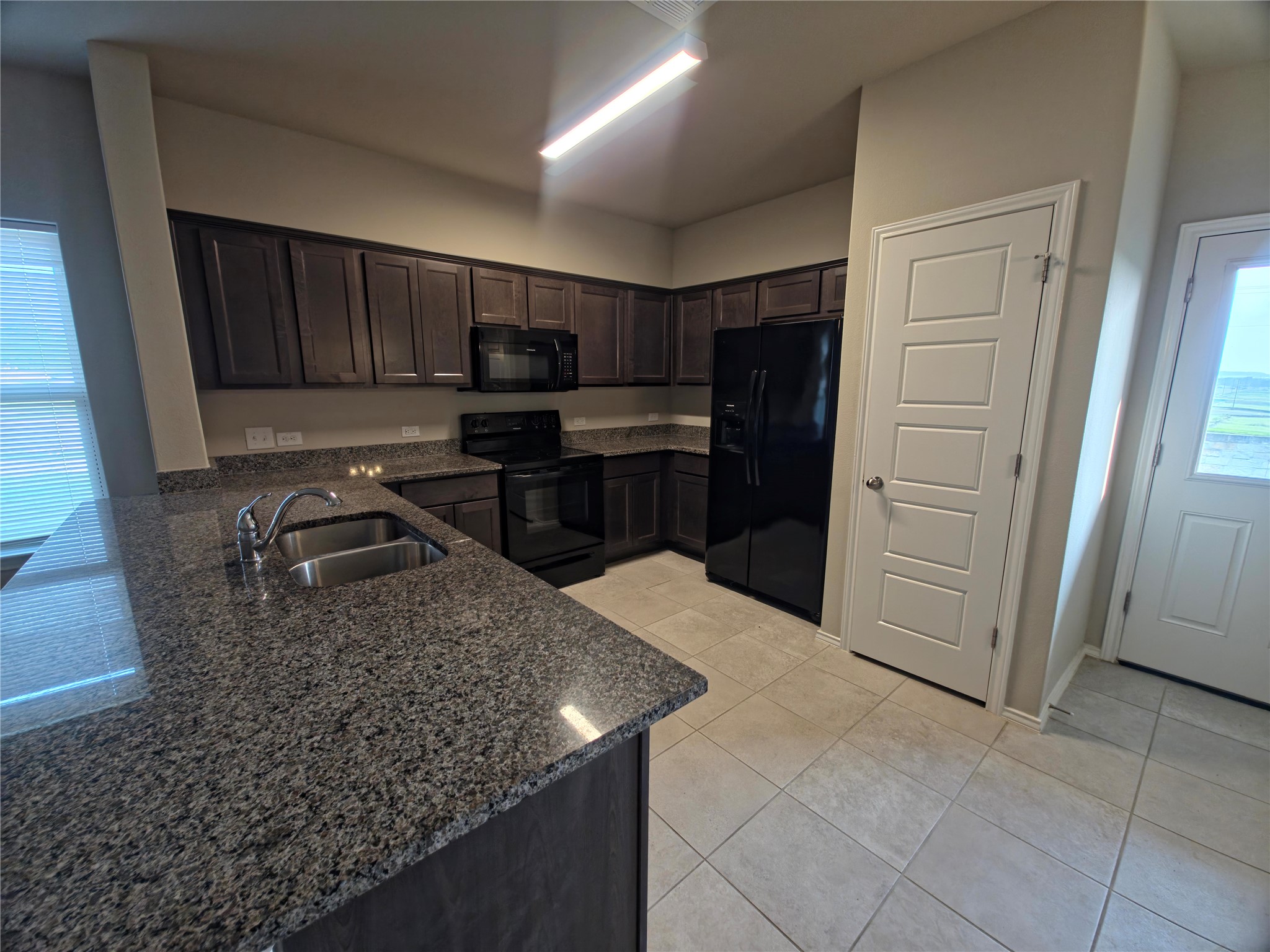 140 Dodge Road Georgetown, TX 78626 - Photo 6 of 14 Kitchen featuring dark wood cabinetry, speckled countertops, and integrated black appliances