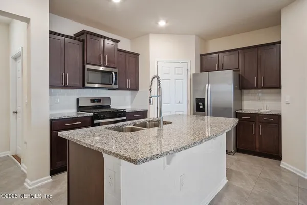a kitchen with stainless steel appliances granite countertop a refrigerator a stove a sink a microwave and cabinets