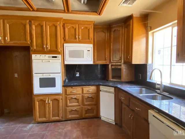 a kitchen with kitchen island a counter top space a sink a refrigerator and a stove