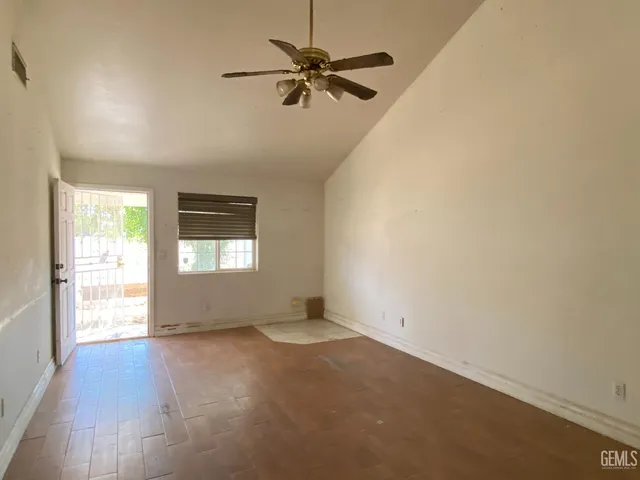 an empty room with wooden floor fan and windows