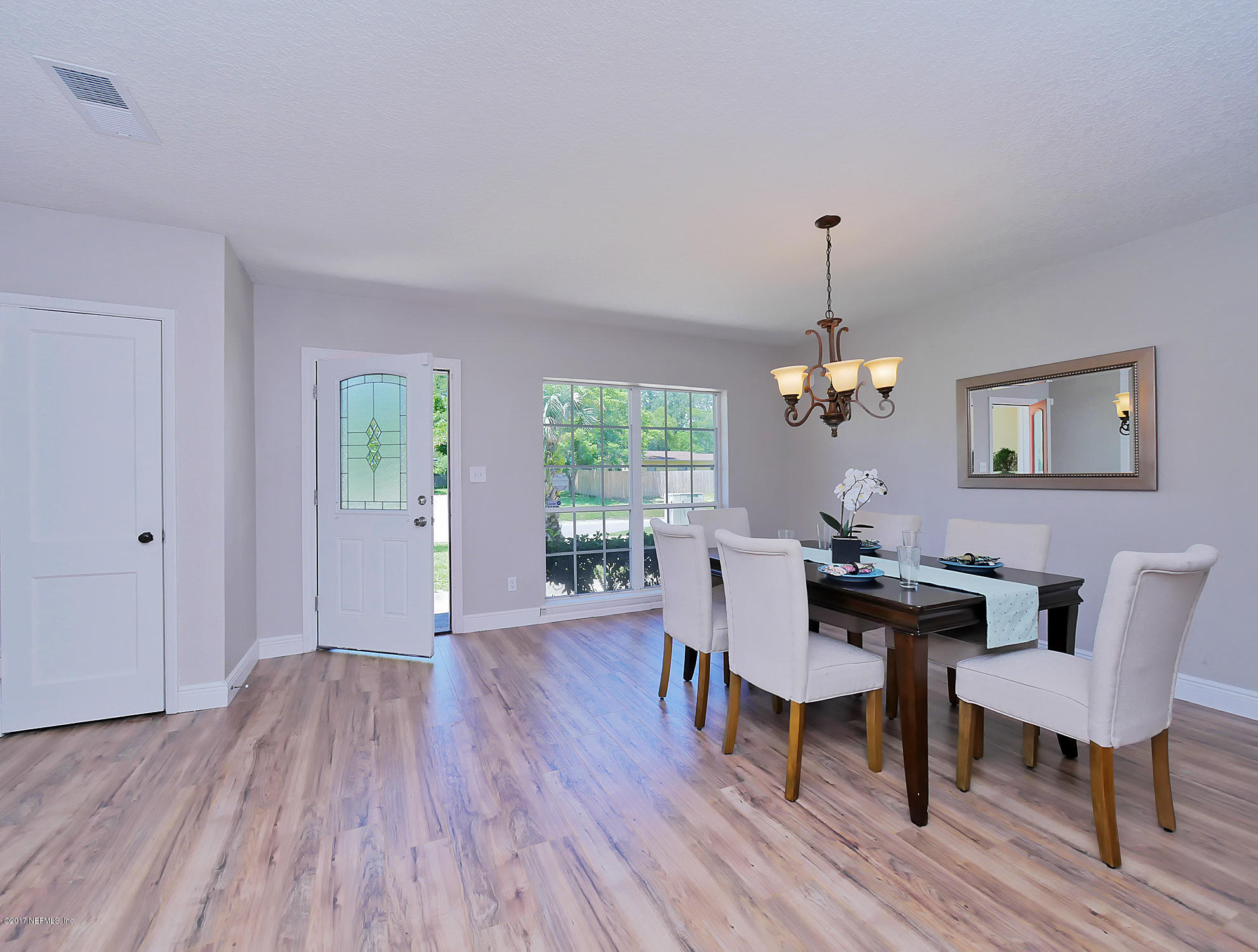 2448 Clemson Road Jacksonville, FL 32217 - Photo 5 of 21 a dining room with wooden floor a chandelier a wooden table and chairs