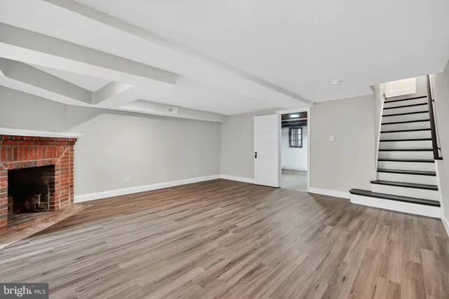 a view of an empty room with wooden floor and fireplace