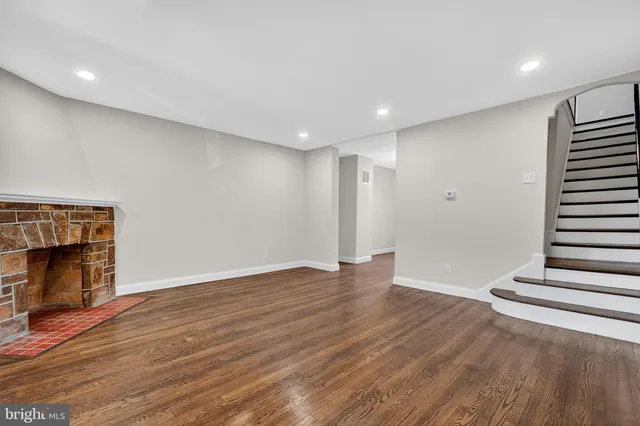 a view of an empty room with wooden floor fireplace and a window