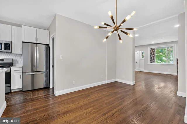 an empty room with wooden floor chandelier fan and windows