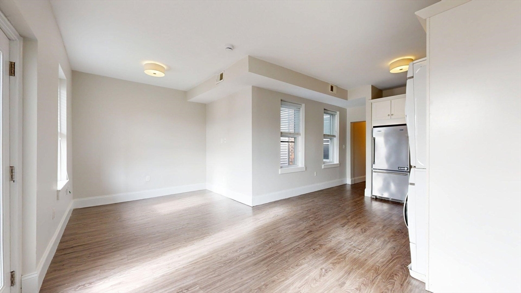 133 Paris Street, Unit 2 Boston, MA 02128 - Photo 1 of 26 a view of an empty room with window and wooden floor