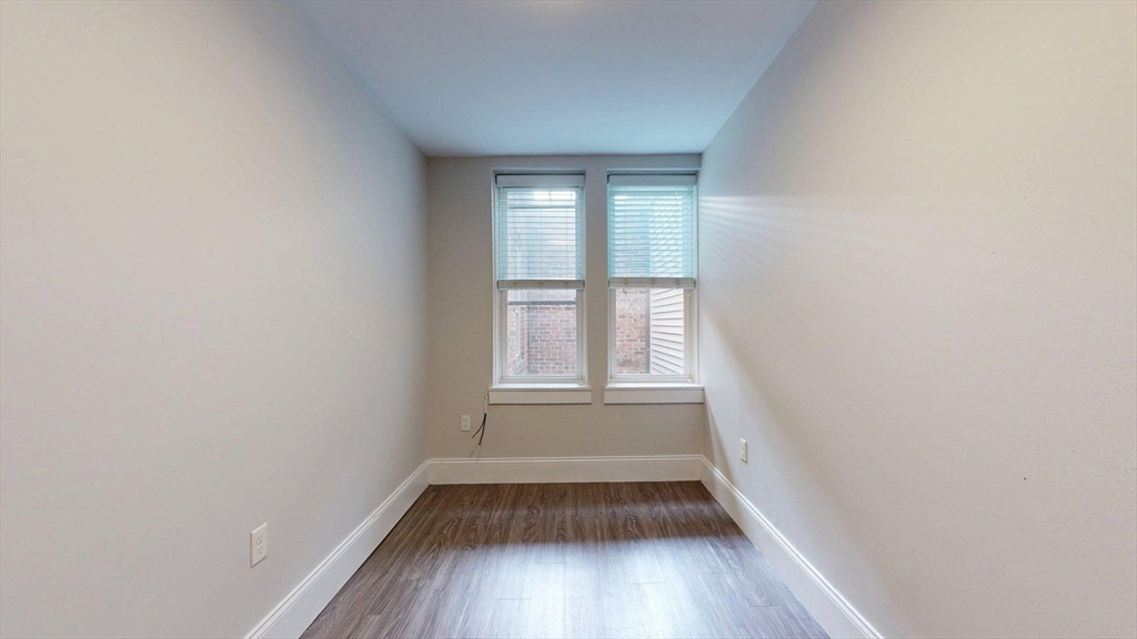 133 Paris Street, Unit 2 Boston, MA 02128 - Photo 11 of 26 an empty room with wooden floor and windows