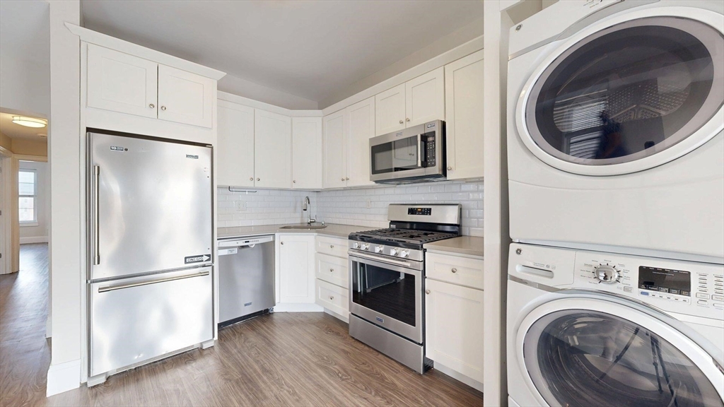 133 Paris Street, Unit 2 Boston, MA 02128 - Photo 16 of 26 a kitchen with cabinets a washer and dryer