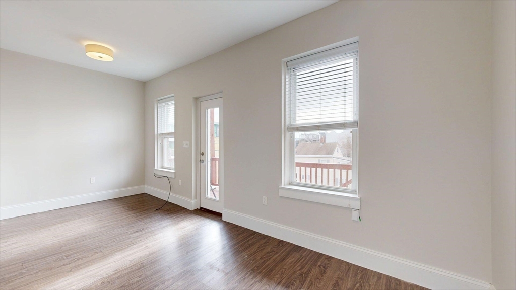133 Paris Street, Unit 2 Boston, MA 02128 - Photo 18 of 26 an empty room with wooden floor and windows