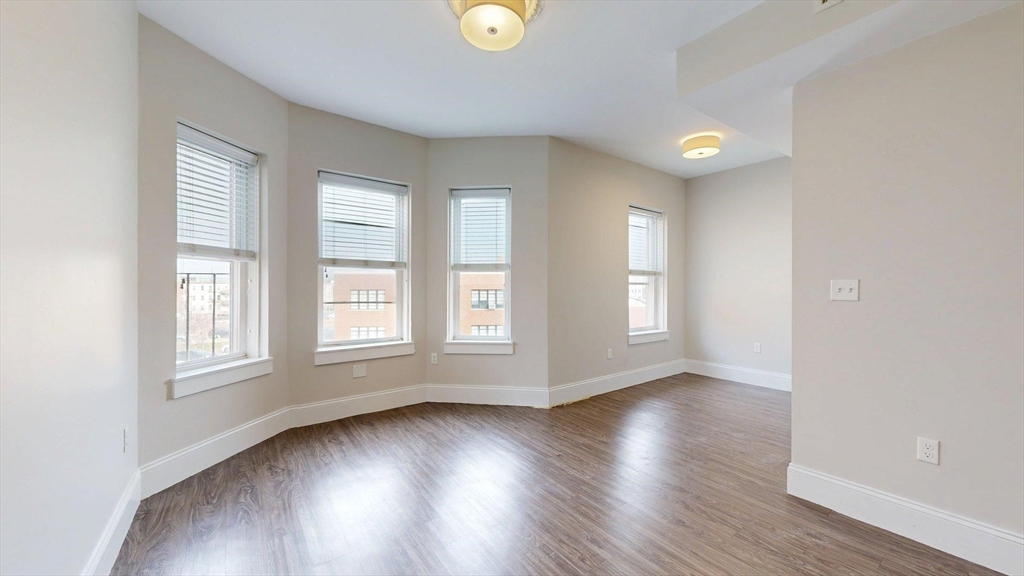 133 Paris Street, Unit 2 Boston, MA 02128 - Photo 4 of 26 an empty room with wooden floor and windows