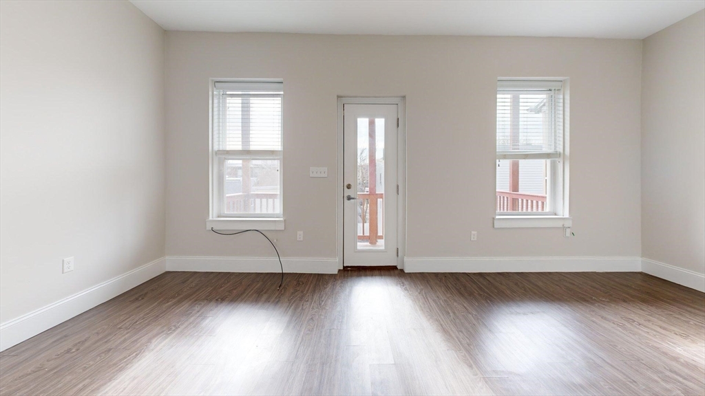 133 Paris Street, Unit 2 Boston, MA 02128 - Photo 5 of 26 an empty room with wooden floor and windows