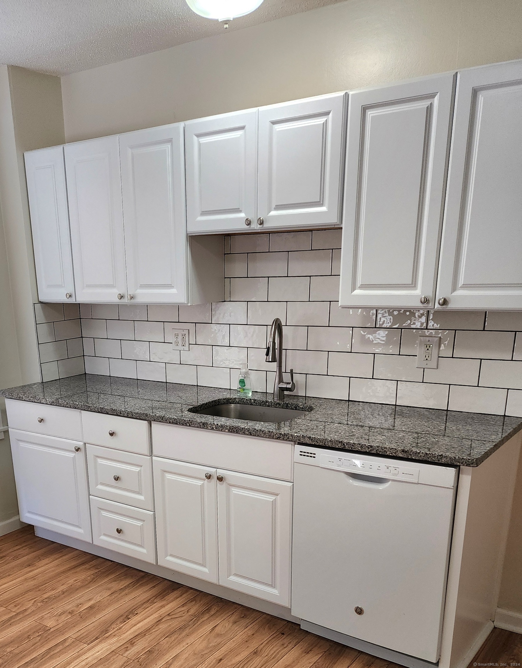 a kitchen with granite countertop white cabinets and a hard wood floors
