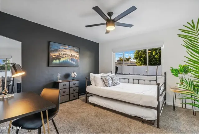 a bedroom with a bed a desk and chair with a bookshelf