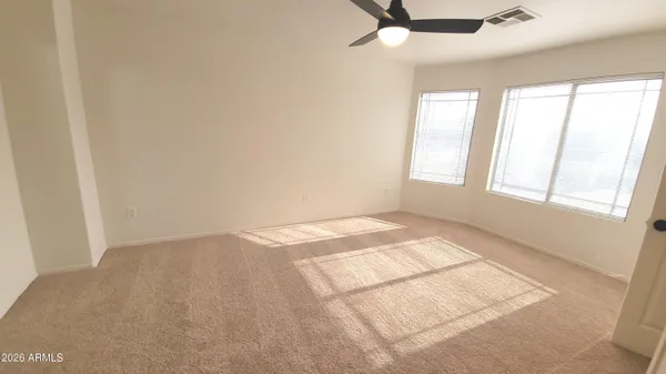 an empty room with windows and chandelier fan