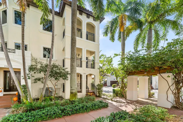 a front view of a multi story residential apartment building with yard and parking