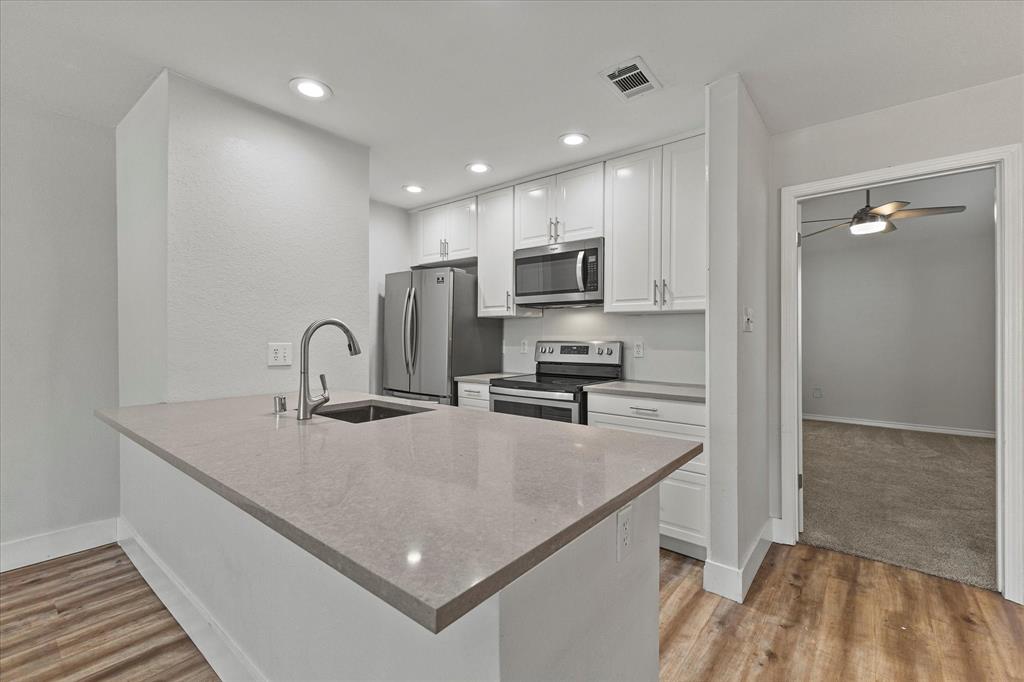 5616 Preston Oaks Road, Unit 208 Dallas, TX 75254 - Photo 3 of 16 a kitchen with kitchen island a sink appliances and cabinets