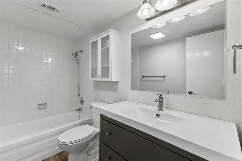 5616 Preston Oaks Road, Unit 208 Dallas, TX 75254 - Photo 7 of 16 a bathroom with a sink a toilet a mirror a bathtub and shower