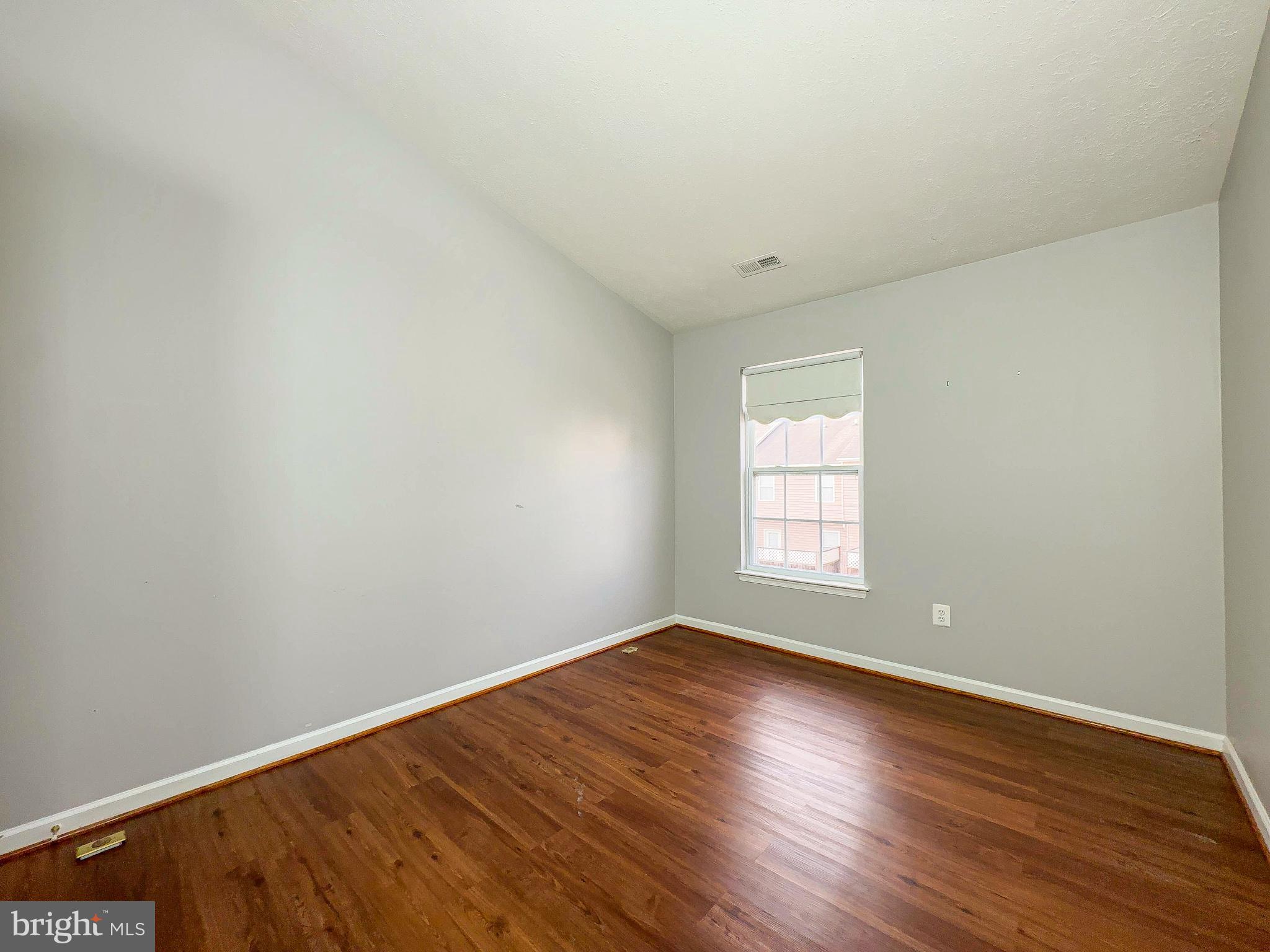 826 Lowe Road Baltimore, MD 21220 - Photo 6 of 35 an empty room with wooden floor and windows