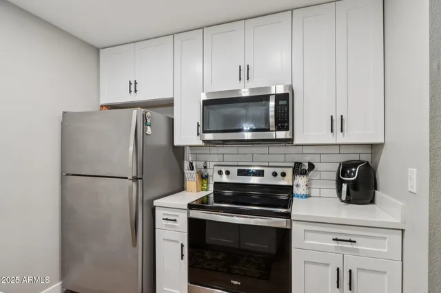 a white kitchen with stainless steel appliances a stove a microwave and a refrigerator