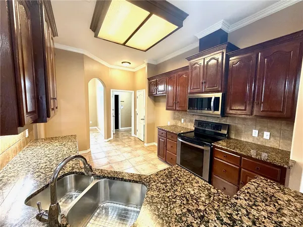 a kitchen with granite countertop a stove a sink and a microwave