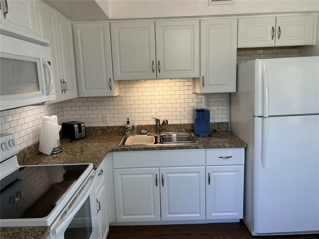 4154 57th Street North, Unit 274 Kenneth City, FL 33709 - Photo 9 of 28 a kitchen with granite countertop a sink stove and refrigerator
