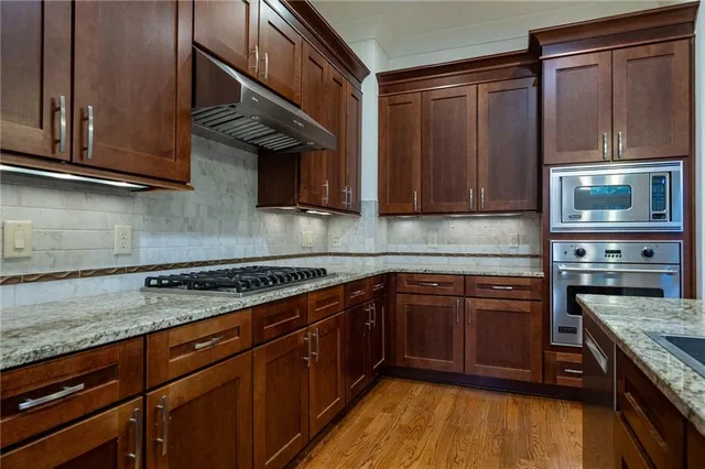 a kitchen with stainless steel appliances granite countertop wooden cabinets and a stove top oven