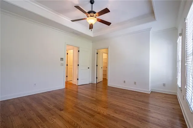 an empty room with wooden floor and a ceiling fan