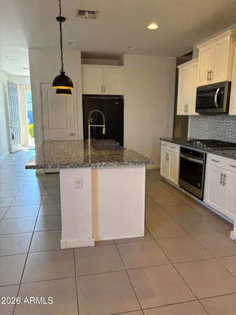 a kitchen with kitchen island granite countertop a stove a sink and a microwave