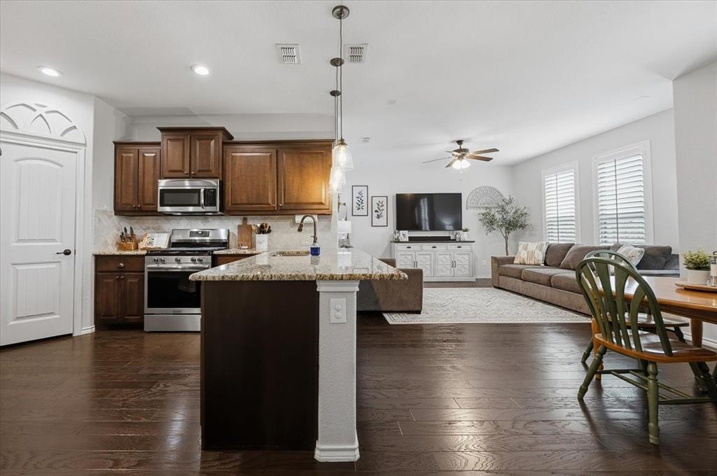448 Spring Drive Saginaw, TX 76131 - Photo 12 of 40 a open kitchen with granite countertop a stove top oven a sink dishwasher a dining table and chairs with wooden floor