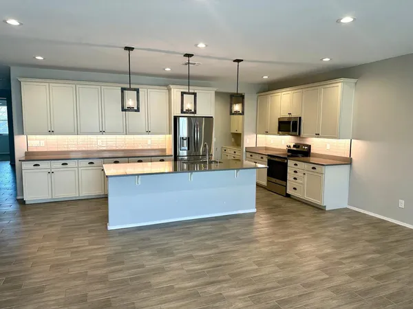 a large kitchen with stainless steel appliances a large counter top a stove and a sink