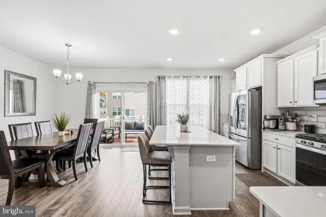 a kitchen with stainless steel appliances granite countertop a stove a sink a microwave a dining table and chairs