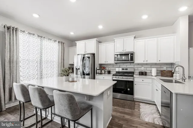 a kitchen with stainless steel appliances kitchen island granite countertop a stove a refrigerator a sink a dining table and chairs