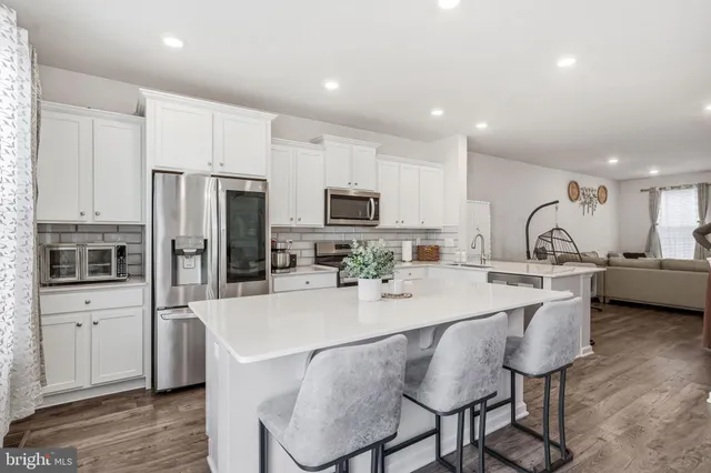 a kitchen with stainless steel appliances granite countertop a stove top oven a sink dishwasher and a refrigerator with the cabinets