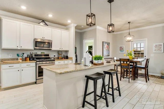 a kitchen with stainless steel appliances granite countertop a stove a sink a microwave a dining table and chairs with wooden floor