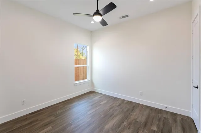 an empty room with wooden floor ceiling fan and window