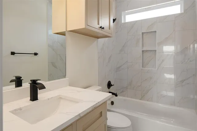 a bathroom with a granite countertop sink toilet and bathtub