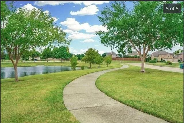a view of a lake with a big yard and large trees
