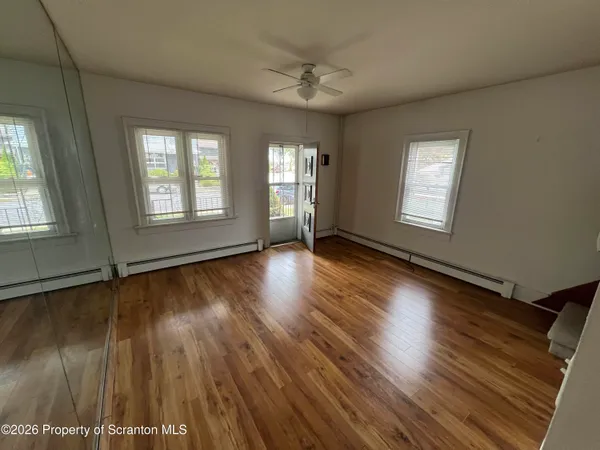 a view of an empty room with wooden floor and a window