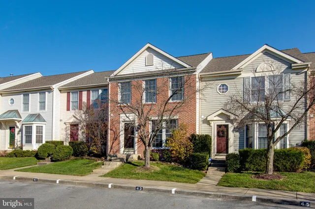 a view of a white house with large windows and a yard with plants and large tree