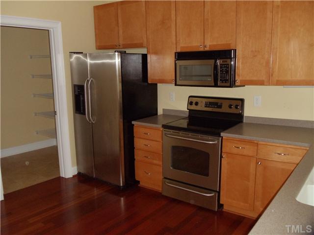 3811 Lunceston Way, Unit 305 Raleigh, NC 27613 - Photo 10 of 25 Kitchen has cherry hardwood floors, maple cabinets, stainless appliances, solid surface tops with integrated sink, a breakfast bar overhang and a huge walk-in pantry!