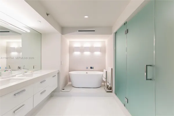 a spacious bathroom with a double vanity sink mirror and bathtub