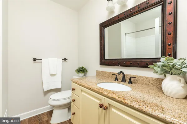 a bathroom with a granite countertop sink mirror and toilet