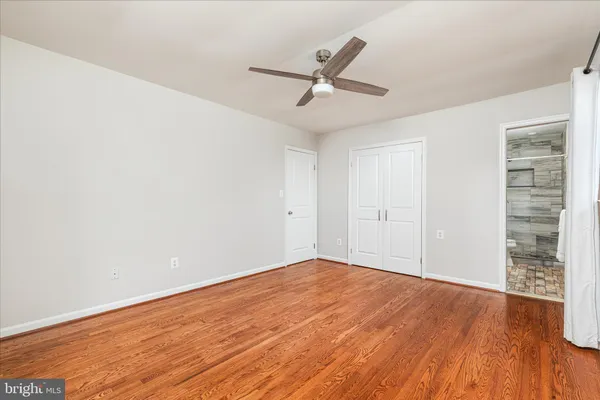 an empty room with wooden floor fan and windows
