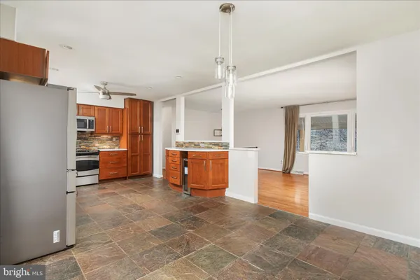 a large kitchen with stainless steel appliances kitchen island granite countertop a refrigerator and a sink